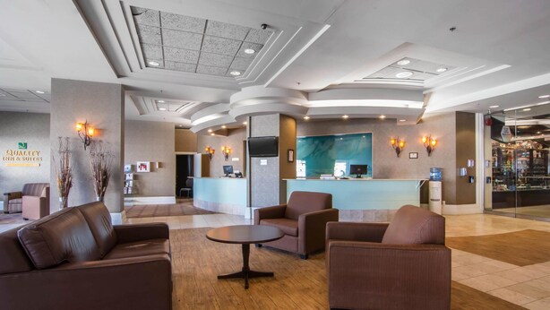 A hotel lobby with a reception desk, seating area, and a large window.