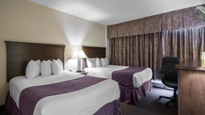 A hotel room with two beds, a desk, a chair, a lamp, and a window with curtains.