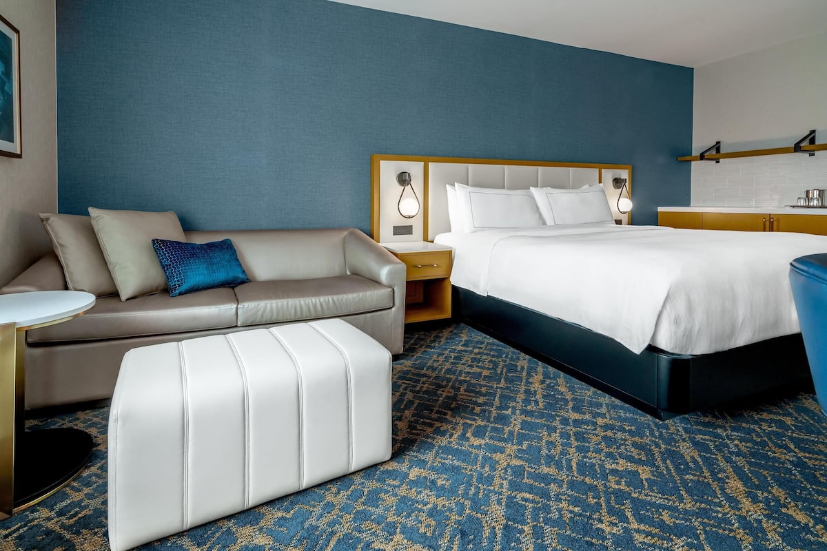 Una habitación de hotel con cama, sofá, una mesita y una mesita de noche.