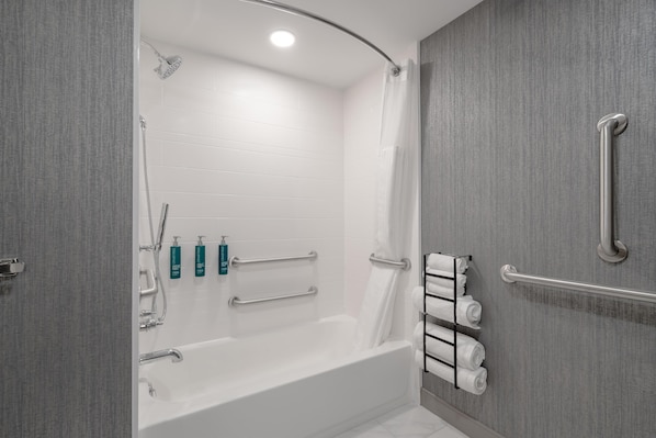 A modern bathroom with a bathtub, grab bars, and a towel rack. - DoubleTree by Hilton Sioux City (Sioux City)