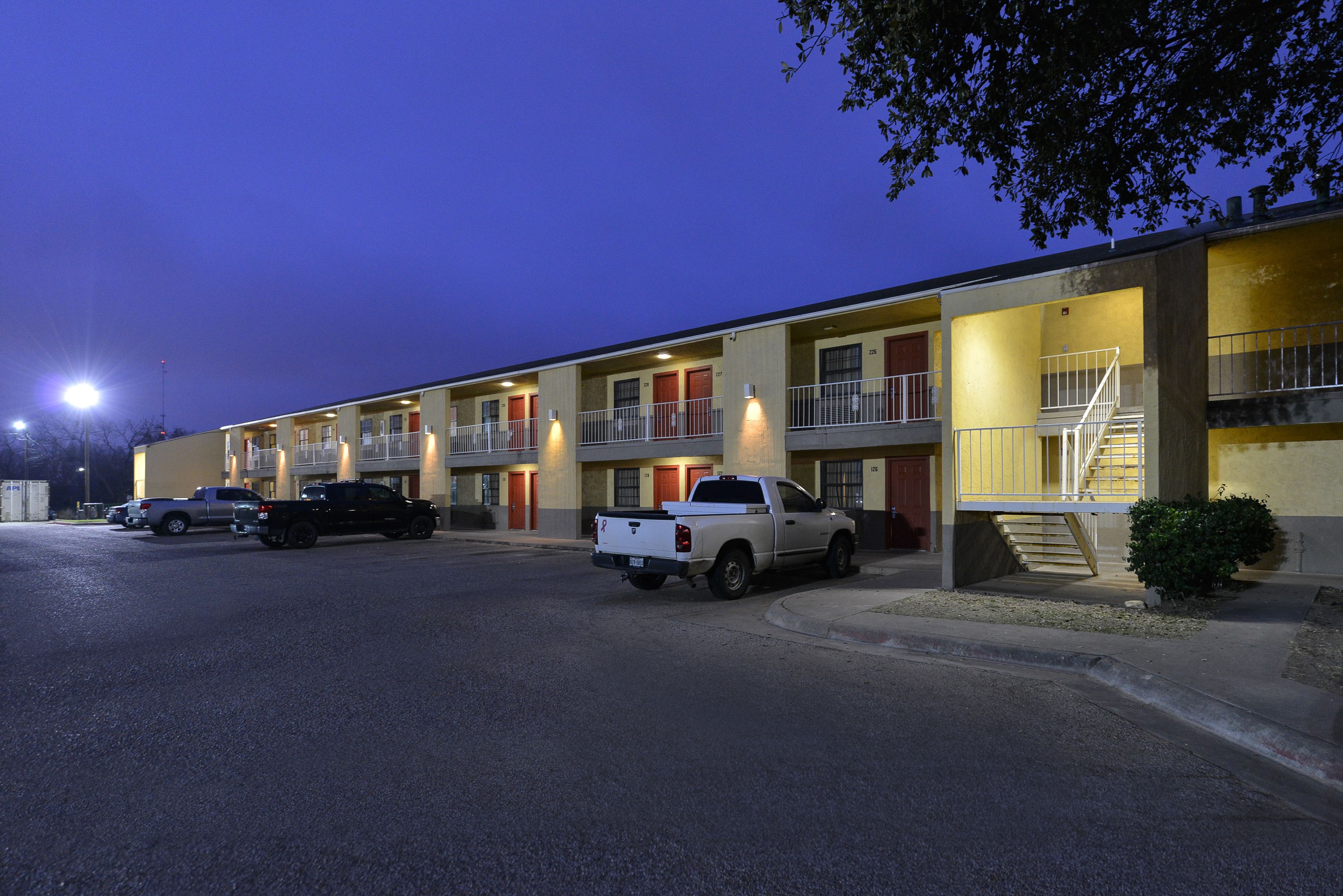 Un motel con varias habitaciones, un estacionamiento y una escalera que conduce al piso superior.
