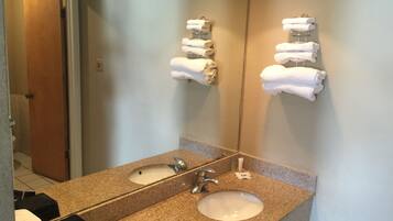 A bathroom with a granite countertop, a sink, and a mirror. There are two towel racks with towels on them.