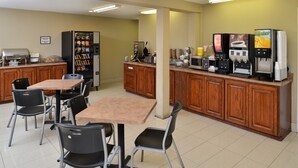 A small, clean room with a table and chairs, a vending machine, a coffee machine, and a microwave. - Inn of the Conchos (San Angelo)