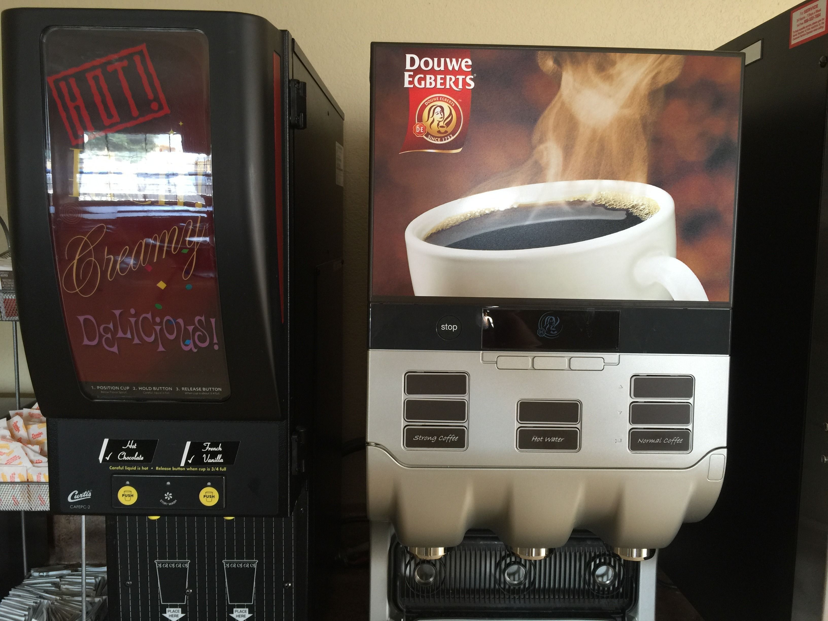 Una cafetera con diseño de taza de café Douwe Egberts y un portavasos.