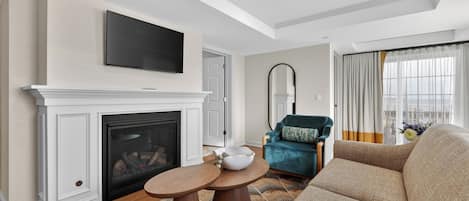 A living room with a fireplace, a television mounted above it, a sofa, and a chair.