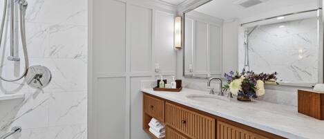 Une salle de bain avec une douche, un lavabo avec un miroir, des meubles en bois et un sol en marbre.
