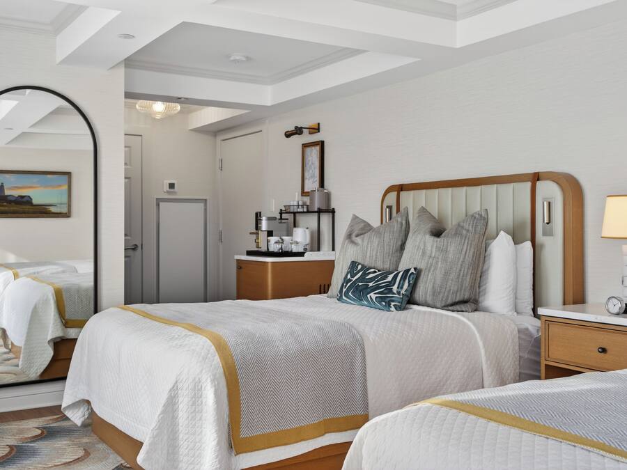 Habitación de hotel con una cama grande, una mesita de noche, un espejo y vistas al pasillo.