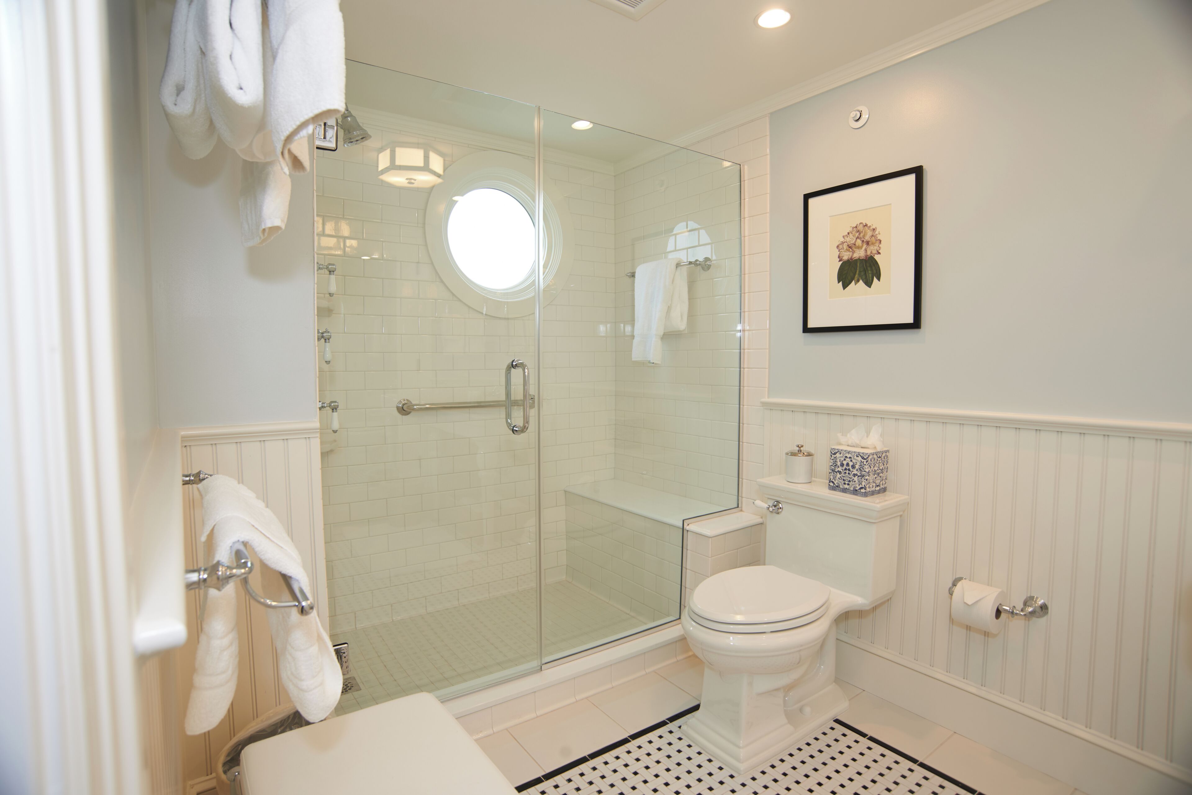 Un bagno con doccia vetrata, un water e un quadro appeso al muro.
