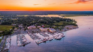 Vue aérienne d’une marina avec des bateaux amarrés, un parking et des bâtiments donnant sur le front de mer.