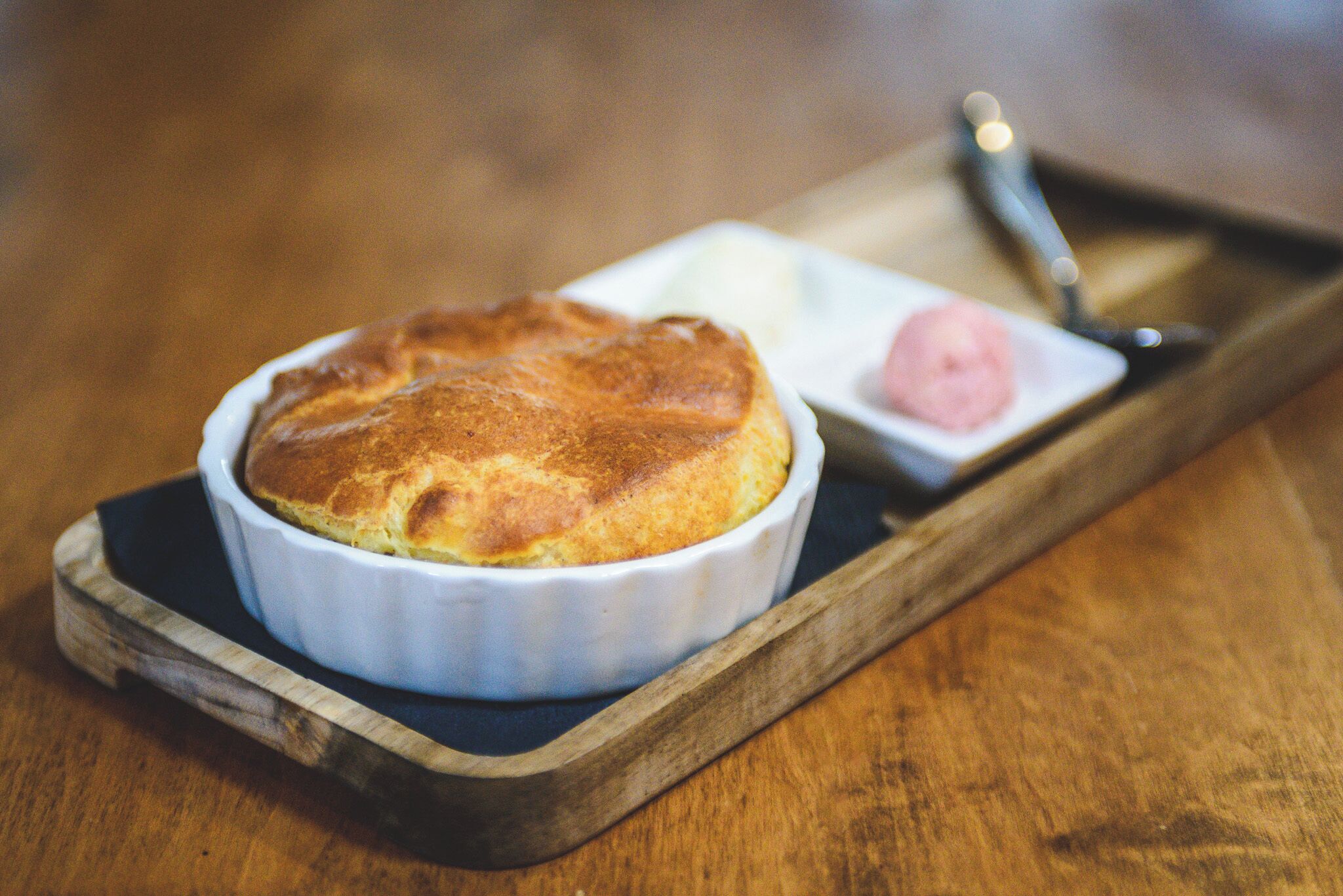 A dessert in a white ramekin on a wooden tray.