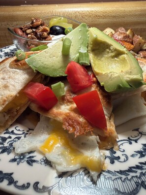 Un plato con un sándwich, rebanadas de aguacate, tomate y un huevo.