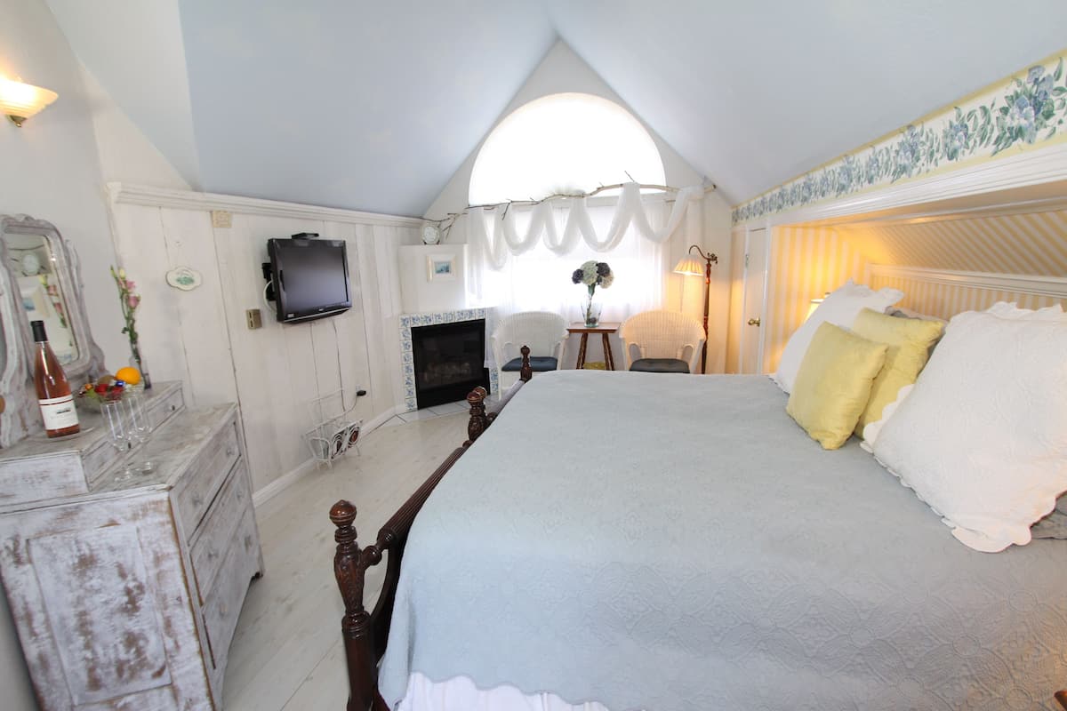 A bedroom with a large bed, a dresser, a television, and a window with curtains.
