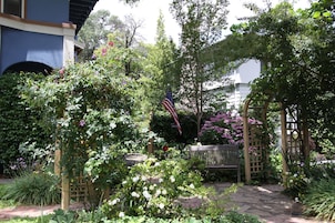 A garden with a wooden bench, a pergola, and an American flag.