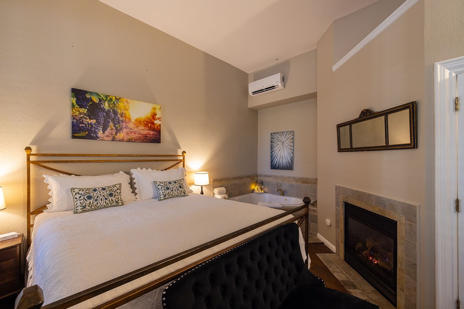 A bedroom with a large bed, a fireplace, and a painting on the wall.