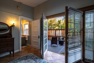 Un interior de vivienda con un baño, un comedor con mobiliario exterior y un patio con cerca de madera.