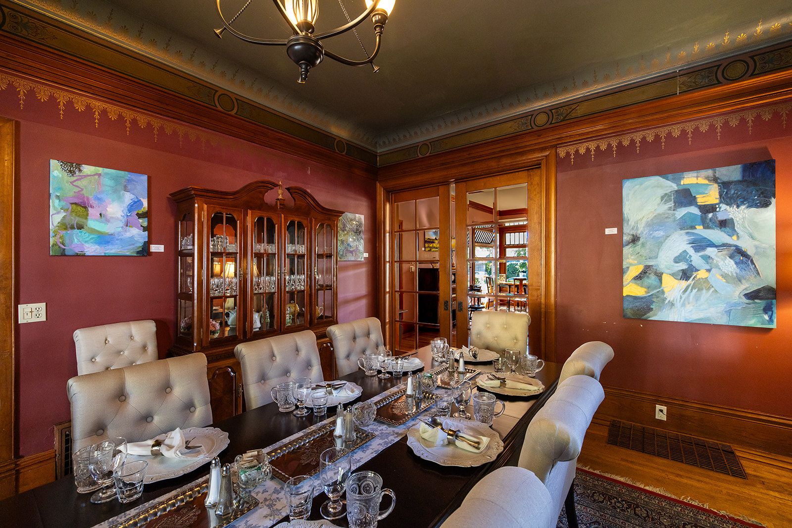 Une salle à manger élégante, avec une longue table dressée pour six personnes, entourée de chaises rembourrées.
