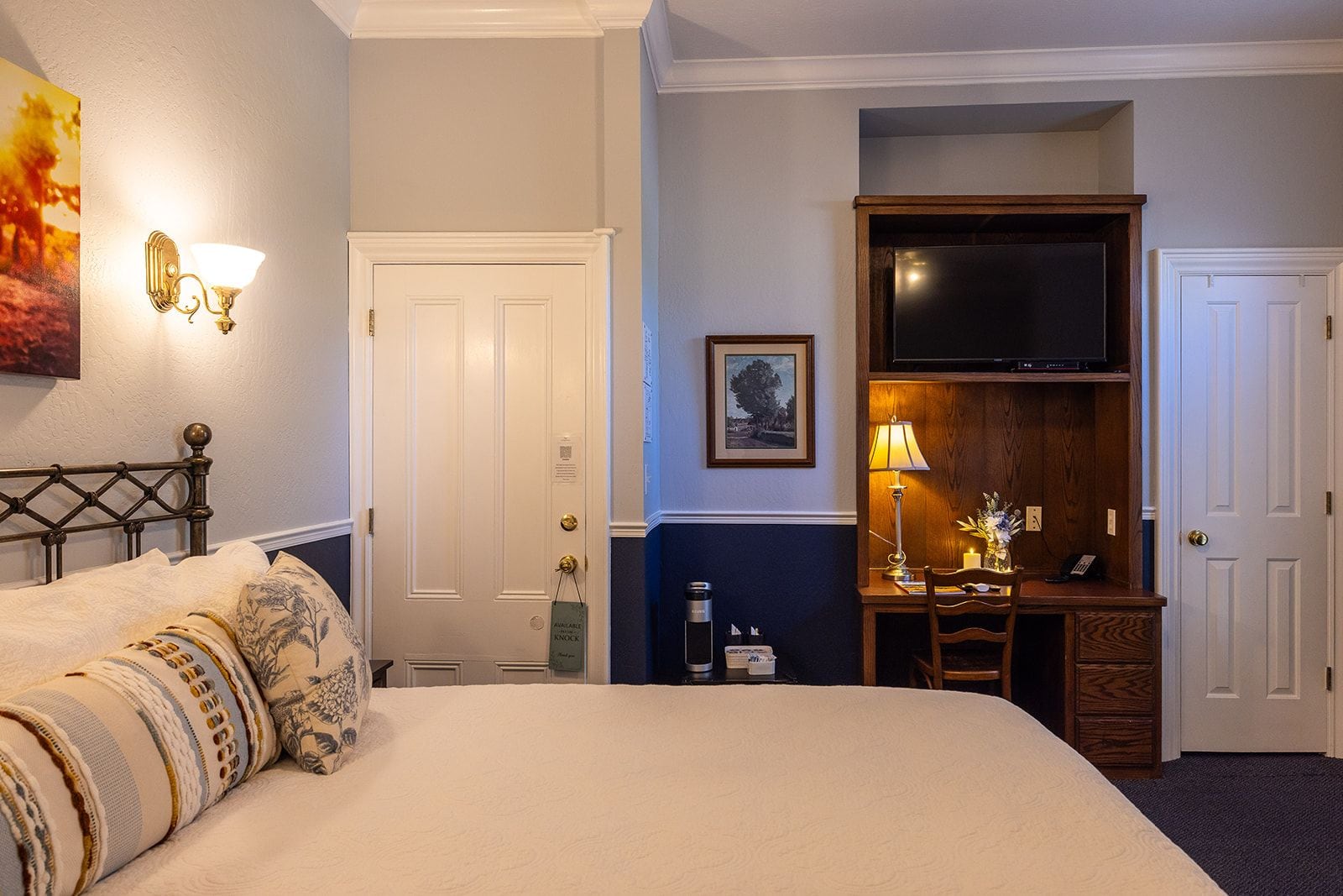 Una habitación de hotel con cama, escritorio, televisor y puerta.
