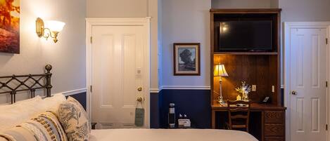 Una habitación de hotel con cama, escritorio, televisor y puerta.