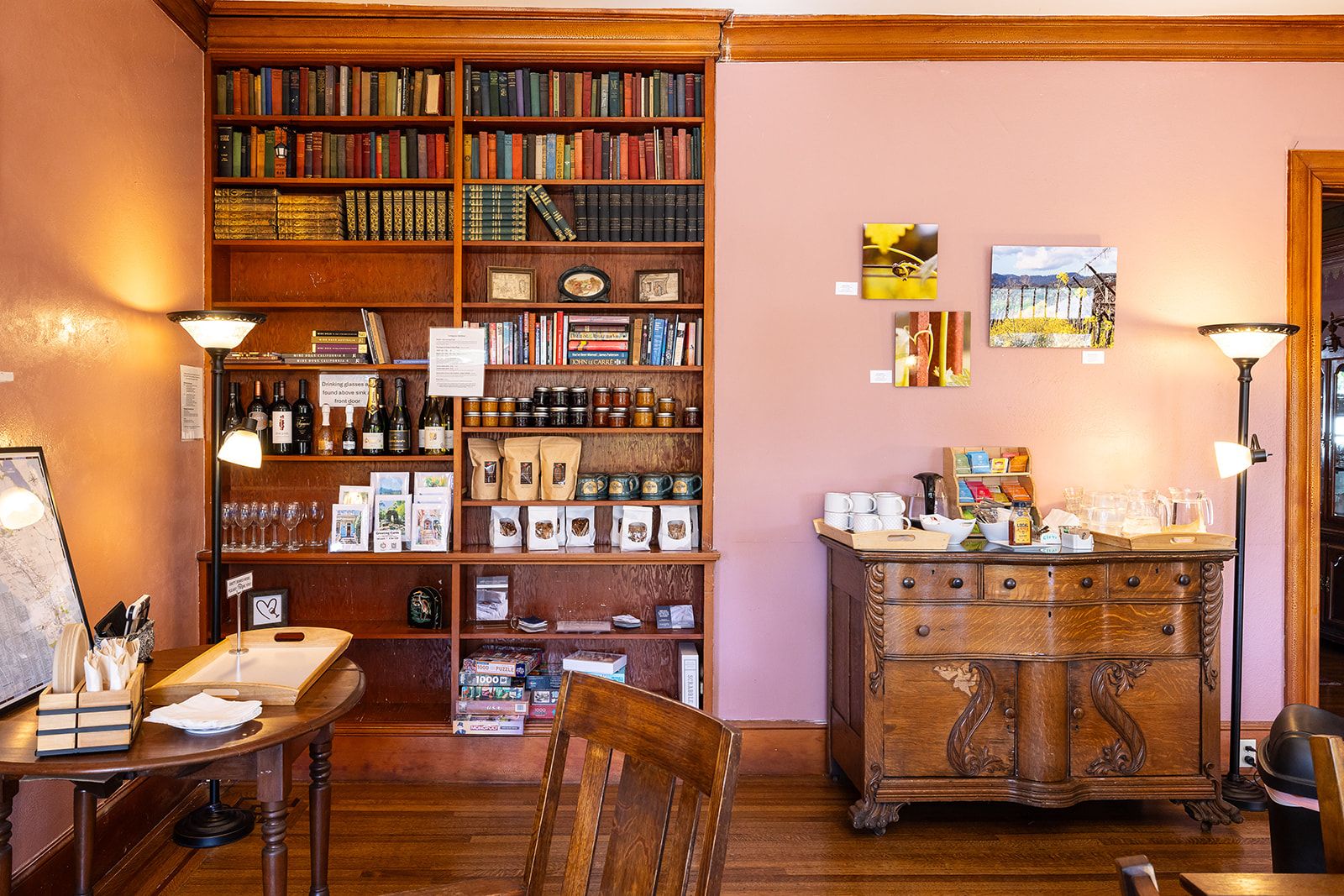 A cozy reading nook with a wooden bookshelf filled with books, a coffee table with reading materials, and a vintage cabinet with decorative items.