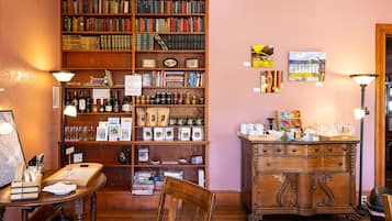 A cozy reading nook with a wooden bookshelf filled with books, a coffee table with reading materials, and a vintage cabinet with decorative items.