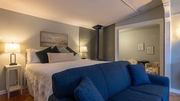A bedroom with a bed, bedside tables, a blue sofa, and a fireplace.