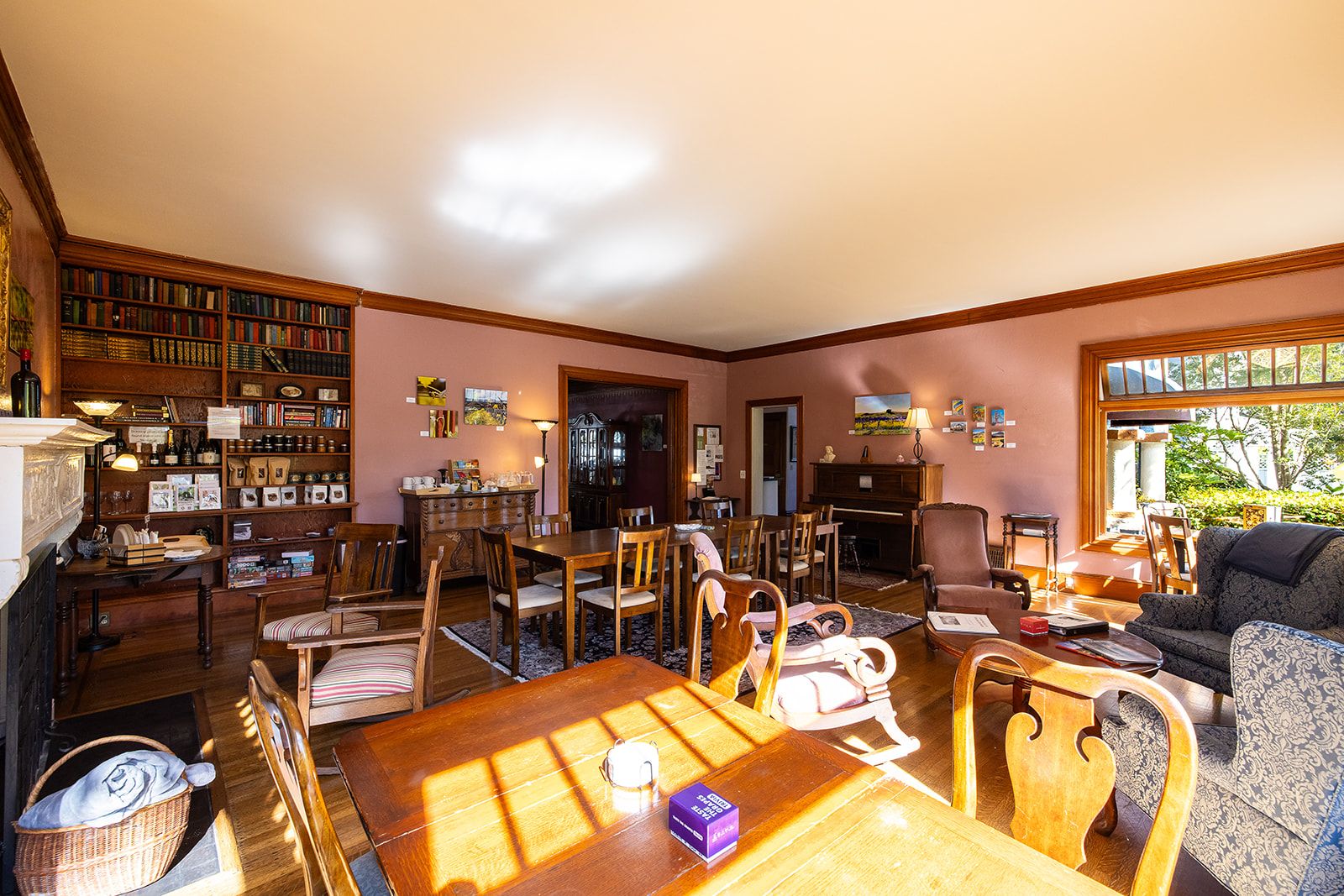 Un salon spacieux comprenant un coin repas, une cheminée et une bibliothèque remplie de livres.