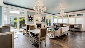 A spacious dining area with wooden chairs and a table, a cozy seating area with a sofa and armchairs, and large windows with decorative glass panels. - White House Napa (Napa)