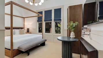 A bedroom with a four-poster bed, a bench, a round table, and a fireplace.