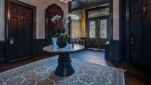 A grand hallway with a round table, dark wooden doors, and a large chandelier. - White House Napa (Napa)