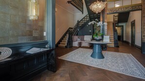 A spacious foyer with a grand staircase, a seating area with a table and chairs, and a decorative chandelier. - White House Napa (Napa)