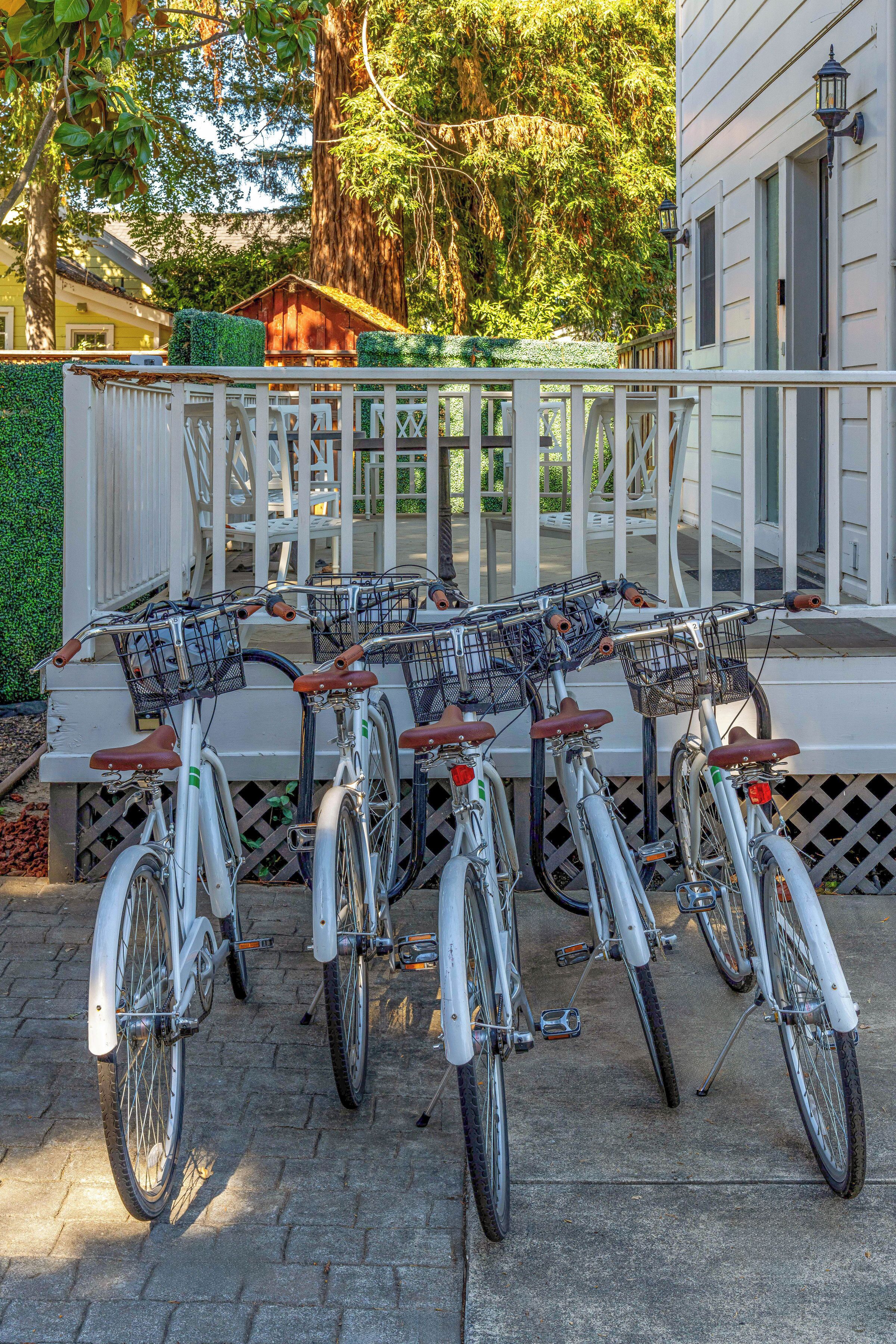 A row of bicycles with baskets, parked on a paved surface.