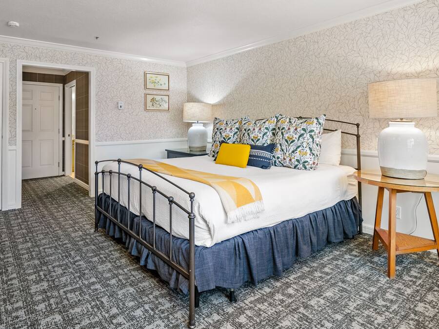 Une chambre à coucher bien rangée, avec un lit, des tables de chevet et une lampe.