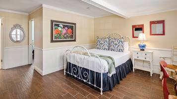 A bedroom with a bed, a nightstand, a lamp, a chair, and a painting on the wall.