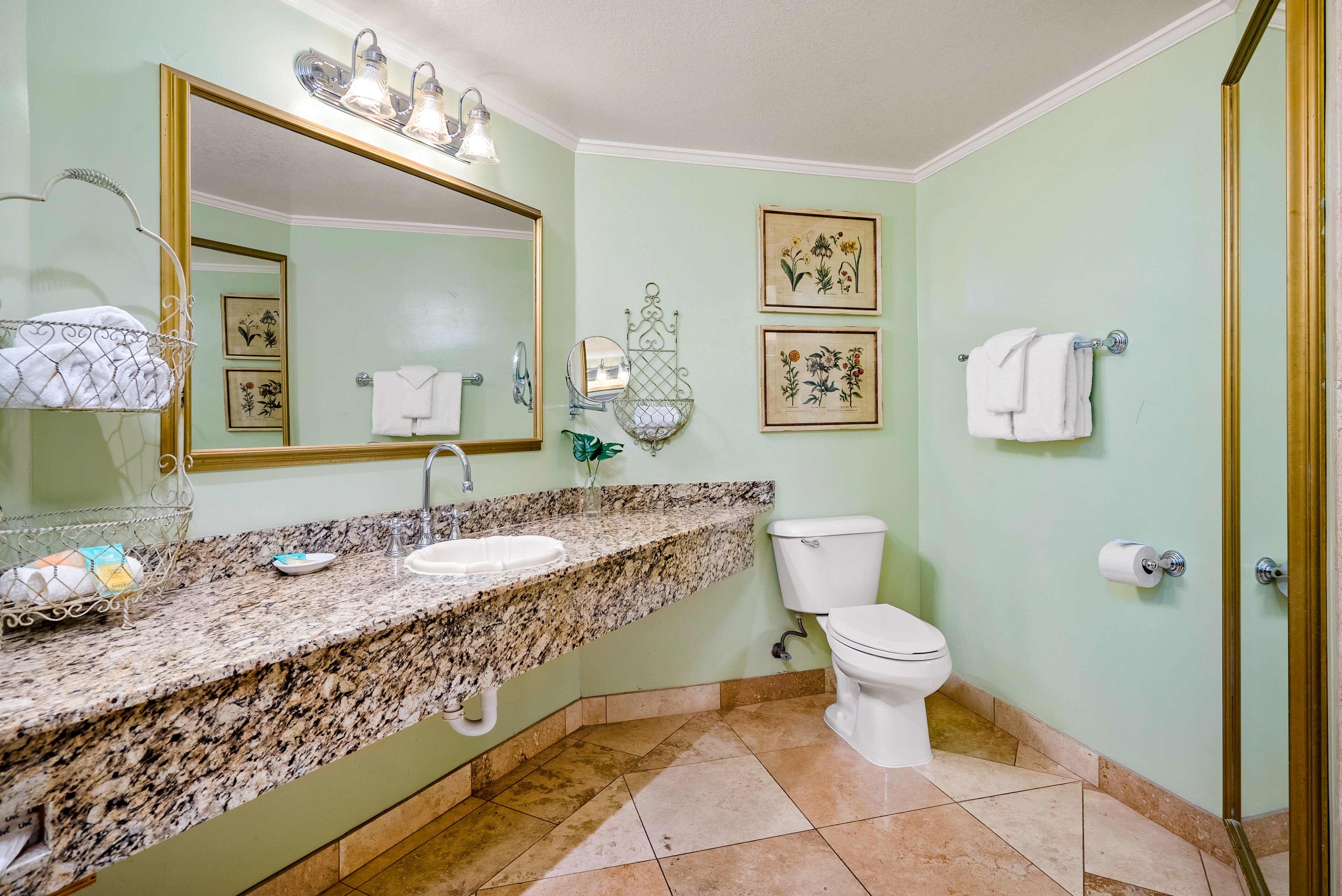 A bathroom with a granite countertop, a white sink, a toilet, and a large mirror.
