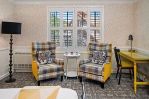 A room with two plaid armchairs, a small round table with a lamp, and a yellow table with a chair. - Apple Farm (San Luis Obispo)