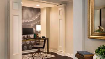 A hallway with a dining area featuring a table, chairs, and a patterned rug.