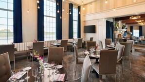 Un comedor amplio con techos altos, ventanas grandes y candelabros modernos.