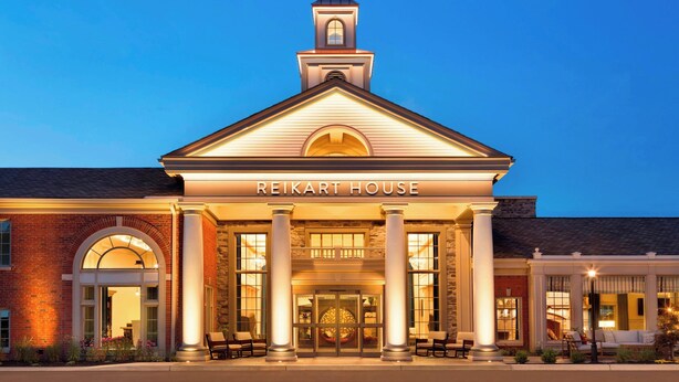 Un hotel con una entrada destacada, una torre del reloj y el nombre "REIKART HOUSE" exhibido sobre la entrada.