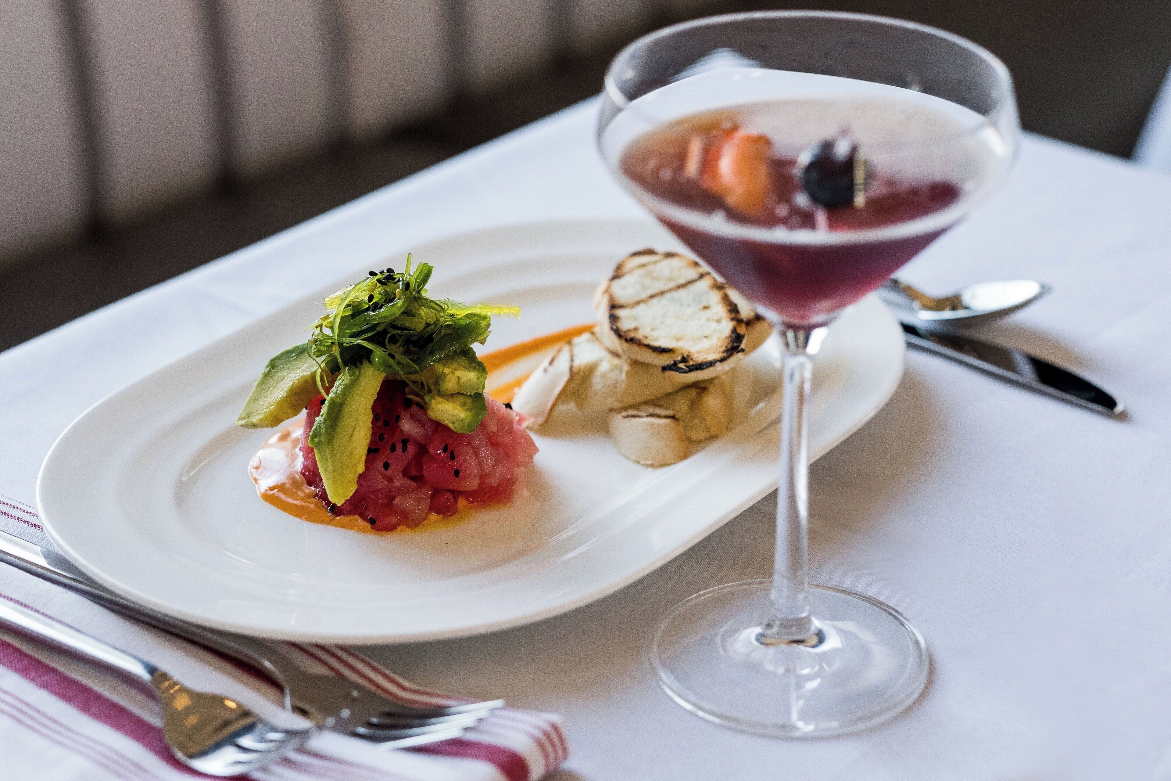 A white plate with a salad, grilled chicken, and a martini glass.