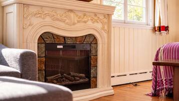 A fireplace with a stone surround, a grey sofa, and a patterned throw blanket.