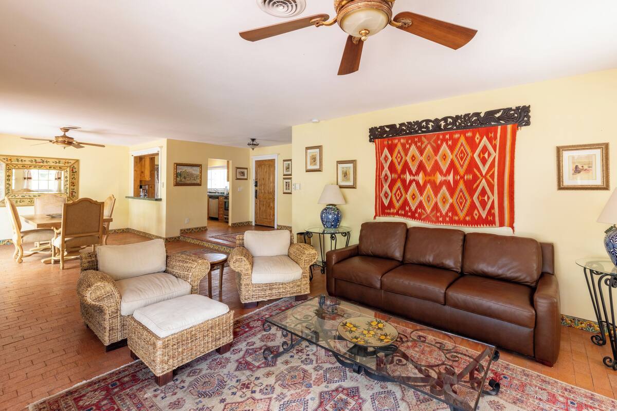 A living room with wicker furniture, a glass coffee table, and a brown leather sofa.