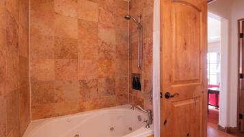 A bathroom with a bathtub, shower, and wooden door.