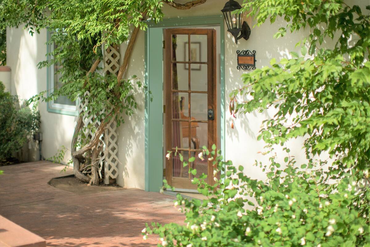 A house with a wooden door, a white wall, and a brick pathway.