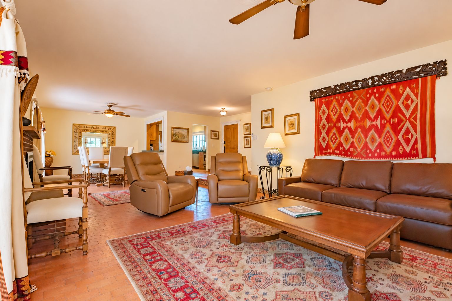 A living room with a brown leather sofa, two recliners, a wooden coffee table, and a patterned rug.