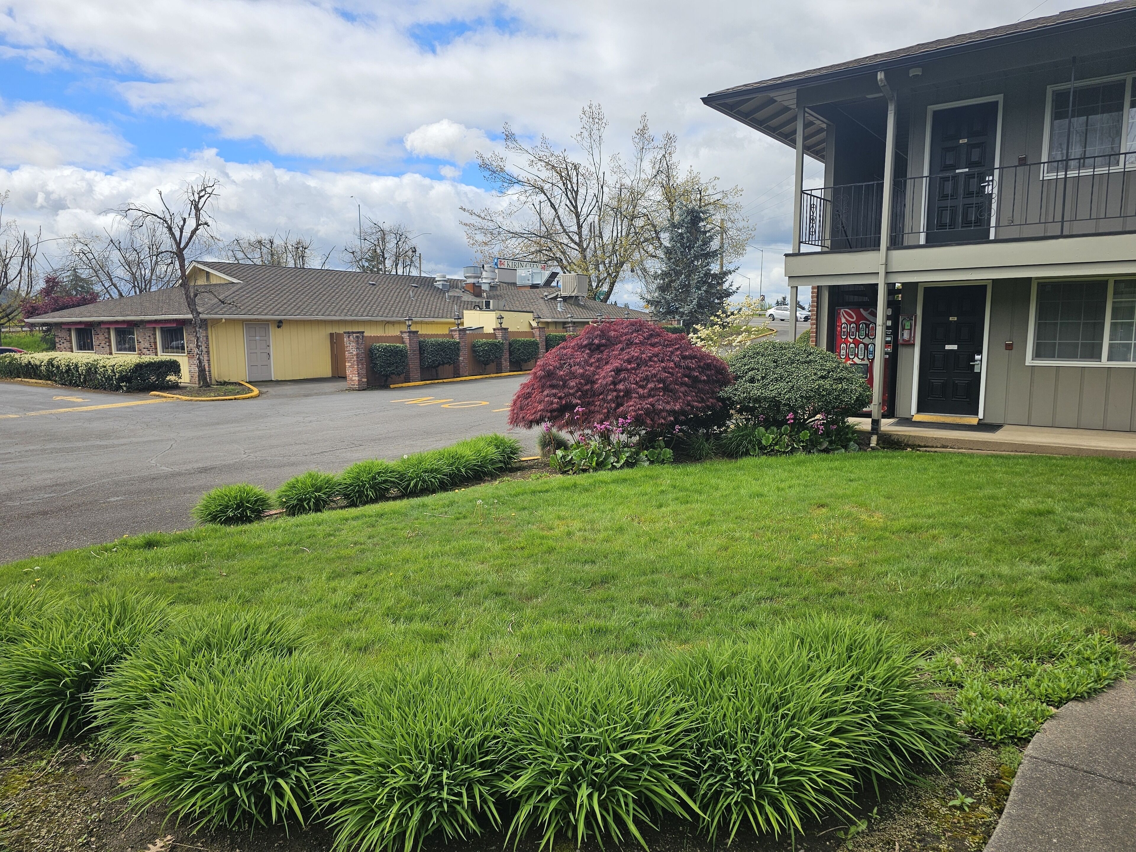 A building with a flat roof, a covered entrance, and a parking lot.