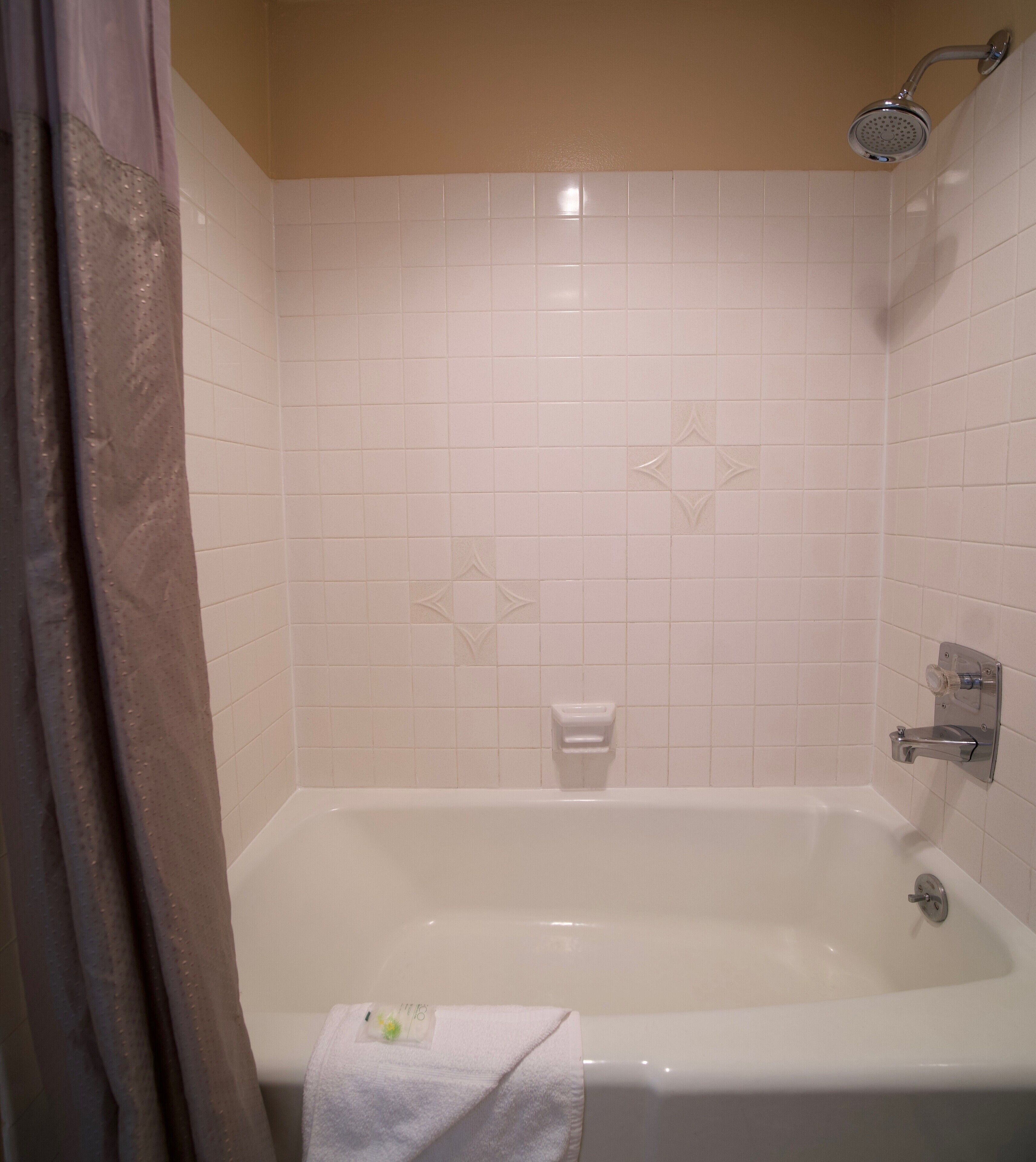 A bathroom with a bathtub, a shower, and a towel rack.
