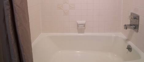 A bathroom with a bathtub, a shower, and a towel rack.
