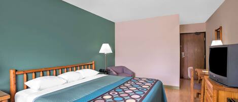 Una habitación de hotel con una cama, un escritorio, un televisor y una silla.
