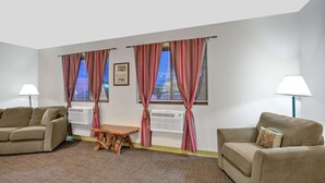 A room with two beige sofas, a wooden table, and two air conditioning units.