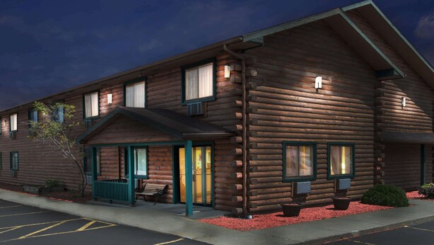 A log cabin-style building with a porch, multiple windows, and a small seating area.